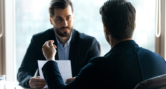 two men in suits in discussion with one another