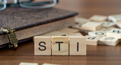 three scrabble pieces spelling STI, an abbreviation for Sexual Transmitted Infection