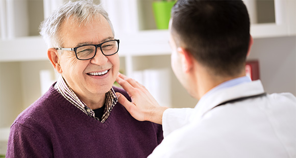 a doctor patting a smiling older man on the shoulder