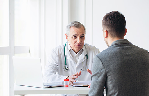 a senior doctor speaking with a patient in a white office