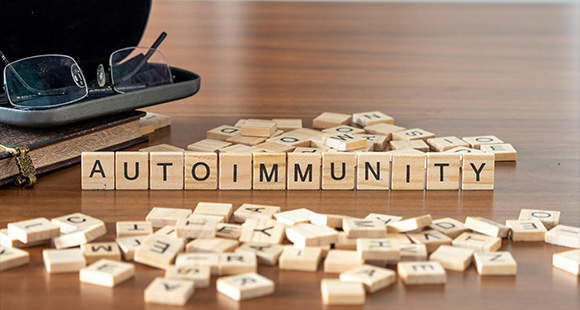 scrabble pieces spelling out autoimmunity next to glasses in a glasses case