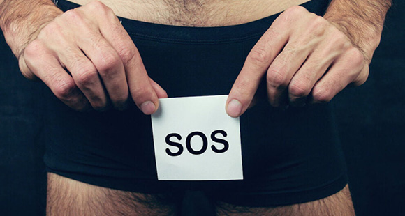 a man in black boxers holding a sticky note reading SOS in front of his groin